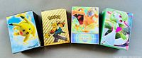 Four separate Pokémon card packages with distinct Pokémon characters printed on each box: Pikachu, Ash with Pikachu, Charizard, and Gardevoir.