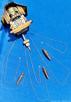 Full clock including wooden dancing figurines, cuckoo bird, clock face with Roman numerals, chains, and pine cone weights.