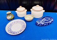 All six pottery pieces displayed on blue cloth, showing variety in shapes, colors, and decoration.