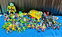 Full view of the TMNT collection on blue surface including large figures, vehicles and multiple small figures.