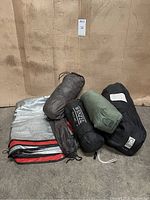 Photo of all packed tents and ground cloths arranged on floor, showing the shapes and storage bags of each item.