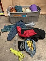 Storage bin with rolled tent bodies, poles, stakes and guy lines