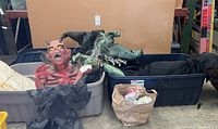 Witch and devil figures packed in plastic containers with additional Halloween props like spider webs and tarps