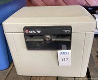 Front view of beige Sentry personal safe model 1170 with black lock panel and keyhole.