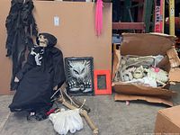 Full view of skeleton dressed in black robe, box with skeleton parts, hanging werewolf decoration, and framed werewolf relief.