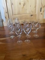 Front view of group of glasses showing cocktail glasses with dot design and wine glasses on wooden floor.