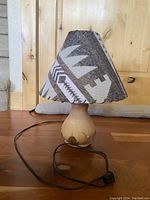 Full view of the lamp showing the carved wooden base with its natural light wood tones and the fabric shade with the Southwest geometric design and leather lacing.