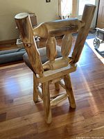 Rear view of one log wood bar stool showing craftsmanship of backrest with natural wood features and joinery.
