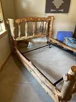 Partial view of assembled log bed frame showing headboard, side rails and metal support rails