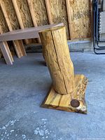 Side view of the handmade log pedestal showing the log mounted vertically on a wooden base with natural edges and wood grain details.