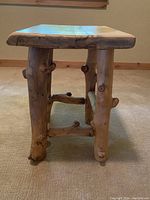Side view of the handmade log side table showing natural log legs with branches and cross supports.