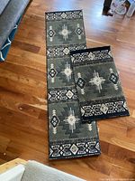 Photo showing two matching Southwest pattern area rugs, one runner and one smaller rug, laid out on a wooden floor.