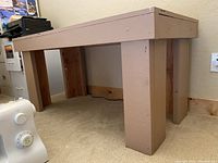 Side view of the handmade small beige work table showing thick legs and frame construction