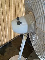 Side view close-up of the fan motor housing and control switches showing the three-speed and oscillation buttons.