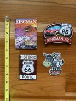 Four Route 66 and Kingman Arizona themed magnets with a yellow measuring tape showing sizes up to about 4 inches.