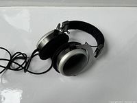 Side angle view of Beyerdynamic T70P headphones showing silver metallic ear cups, black velour ear pads, and black headband with cable.