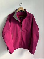 Front view of pink Patagonia women's jacket hanging on a wooden hanger, showing full zipper and pockets.