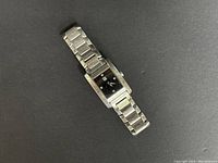 Full view of rectangular women's watch with stainless steel linked bracelet on black background.