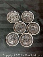 Six clear glass coasters with pinwheel patterns arranged on a dark fabric background showing their tops.