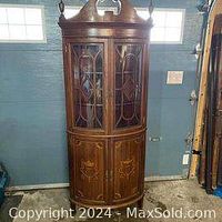Full view of the antique Edwardian corner curio cabinet showcasing curved glass doors and carved wood details.