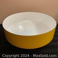Side view of the enamel bowl showing the yellow exterior and white interior.