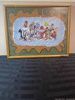 Front view of framed Looney Tunes embroidery on denim fabric with painted abstract background.