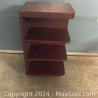 Front view of freestanding solid wood corner shelf showing four shelves and the general shape.