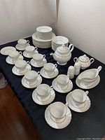 Overview of the entire Johnson Bros. Snow White Regency ironstone dish set laid out on a table showing tea cups, saucers, plates, and other items.