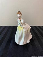 Front view of Royal Doulton porcelain figurine showing woman in detailed white gown holding a red rose.