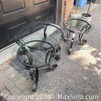 Top view of round wrought iron side tables with scroll legs and glass tops showing some rust and wear.