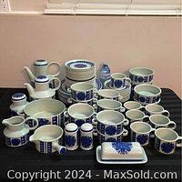 Full view of all items in the Stonehenge Midwinter Ltd Blue Dahlia dinnerware set showing plates, mugs, jugs, bowls, and serving dishes arranged on a surface