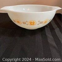 Side view of the white glass bowl with orange and brown floral pattern and left pouring lip