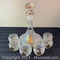 Photo showing vintage Bohemian crystal decanter with frosted bottom, gold nautical ships on front, clear round stopper with gold accent, surrounded by 6 matching roly poly glasses with gold nautical ships and gold rim.