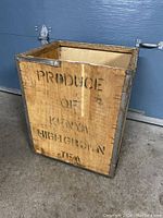 Front view of wooden and metal crate with wording 'Produce of Kenya Highgrown Tea'. Shows condition and lettering clearly.