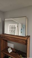 Front view of rectangular medicine cabinet with mirrored door resting on wooden shelving unit.