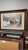 Full view of the framed winter scene painting showing two horses pulling a sled in snowy woods.