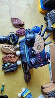 Wide view of the sports lot items arranged on the floor, showing baseball gloves, baseballs, catcher's mask, gloves, and some protective gear.