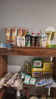 Front view showing multiple bottles of shaving cream, Nivea skin lotion, cosmetic pads, and other toiletry items on wooden shelves.