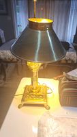 Decorative metal table lamp with brass finish and black shade, lit and working.
