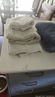 Stack of folded white, cream, and dark gray towels on table.