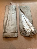 Two stacks of folded gold taupe panels on carpet showing full set