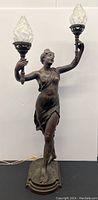 Full view of the lamp showing the female figure, twin torches with glass shades, and base