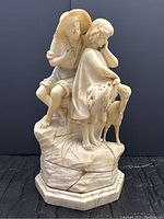 Front view of the alabaster sculpture showing two child figures and a goat on octagonal marble base