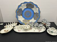 Front view of entire lot showing all included porcelain china pieces on a black surface.