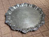 Full top view of round silver plated engraved tray showing detailed elaborate border and floral engraving