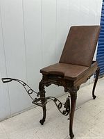 Full view of exam table showing padded adjustable backrest, upholstery and stirrups