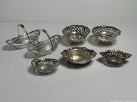All seven sterling silver dishes arranged in two rows on white background