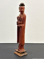 Front view of carved Bakelite figurine of woman holding flower pot, showing detailed face and clothing.