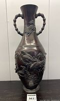 Front view of tall bronze vase showing detailed relief of birds perched on blossom branches and bamboo-style handles