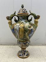 Front view of urn showing hand-painted scene and female nude handles